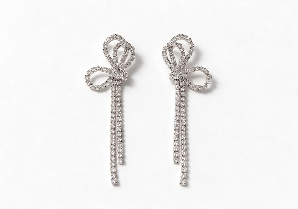 Silver-tone earrings featuring a large hollow pave bow with two short cascading crystal tassels.