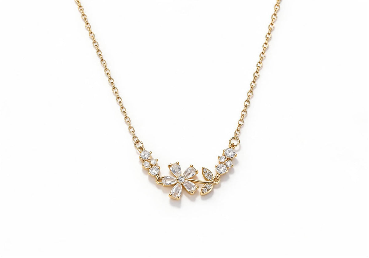 Gold-plated brass necklace featuring a delicate flower and leaf pendant with white zirconia stones