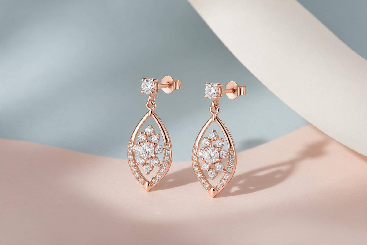 MAROVA JEWELS rose gold marquise open-frame drop earrings with clustered diamond center and pavé detailing, elegant dangle earrings styled on soft pastel blue and blush satin background, luxury fine jewelry product photography