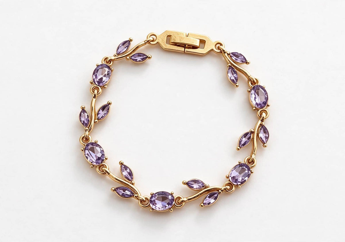 Gold-toned leaf vine bracelet with deep purple amethyst crystal stones on a beige velvet display box