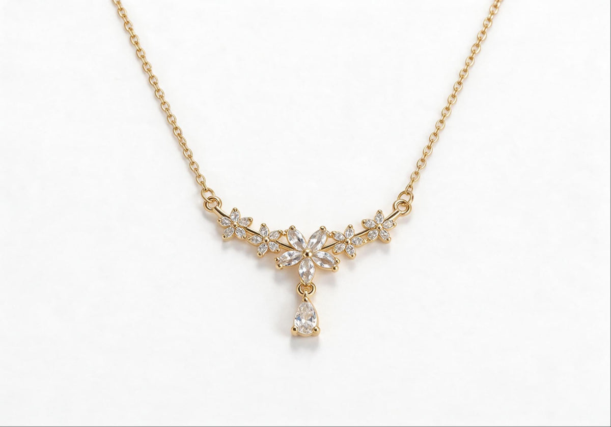 Gold-plated statement necklace featuring five zirconia flowers and an oversized zirconia drop pendant