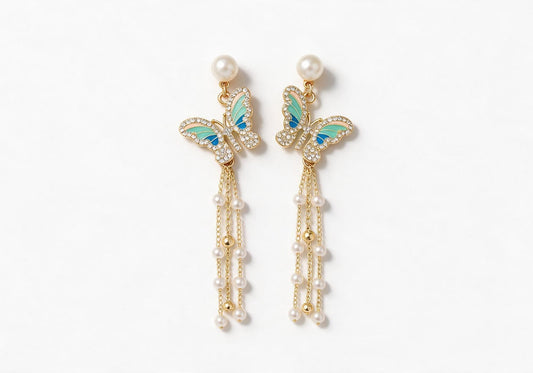 Gold-tone earrings featuring a faux pearl stud, a blue-green gradient enamel butterfly with pave edges, and cascading slender chains with faux pearls and gold beads.
