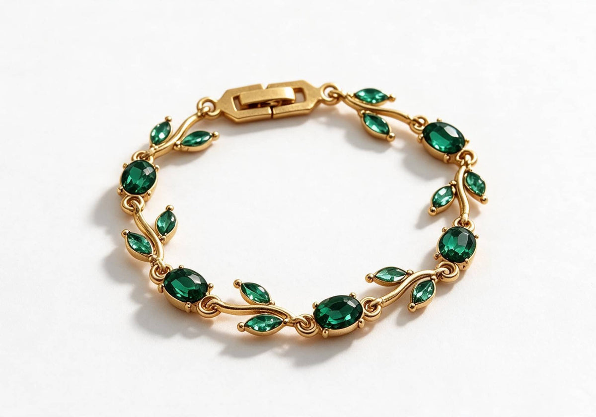Gold-toned leaf vine bracelet with emerald green crystal stones on a beige velvet display box