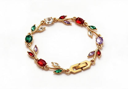 Gold-toned leaf vine bracelet with mixed red, white and green crystal stones on a beige velvet display box