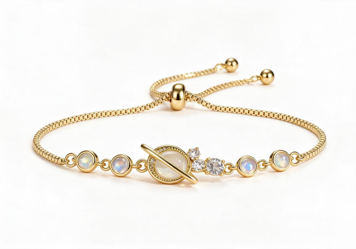 Gold box chain adjustable bracelet featuring a Saturn-inspired iridescent moonstone centerpiece with metal rings and clear zircon accents.