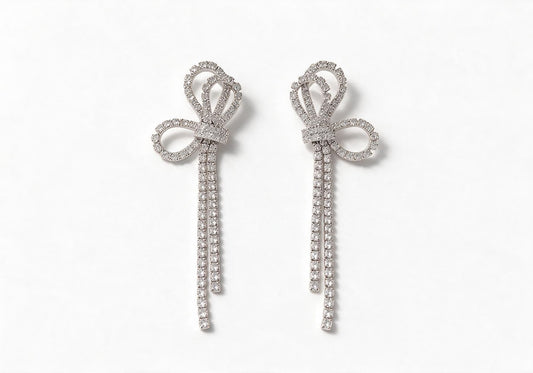 Silver-tone earrings featuring a large hollow pave bow with two short cascading crystal tassels.