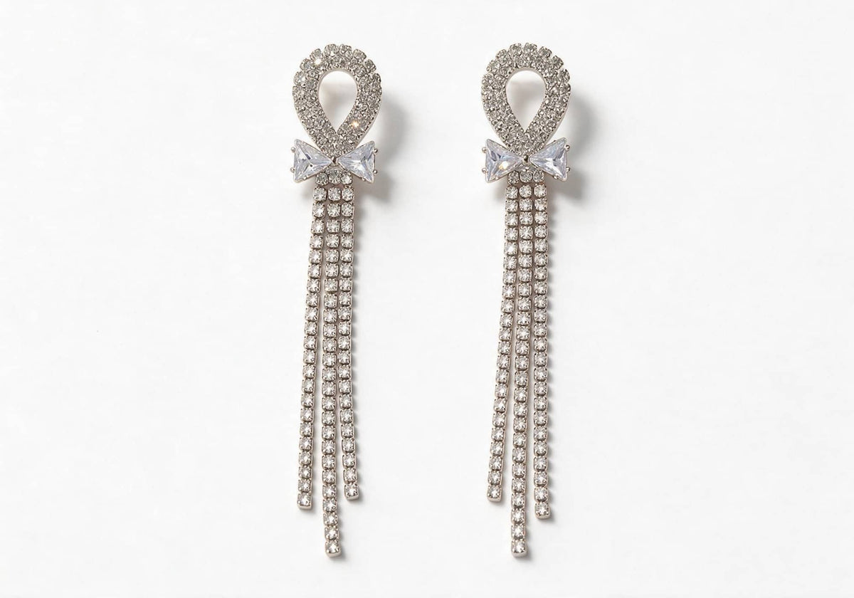 Silver-tone earrings featuring a hollow pave ring, a bow made of square rhinestones, and cascading pave chain tassels.