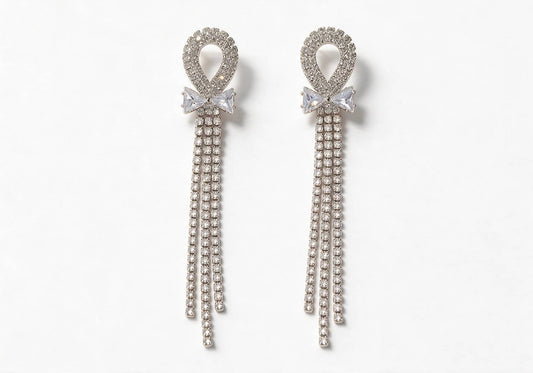 Silver-tone earrings featuring a hollow pave ring, a bow made of square rhinestones, and cascading pave chain tassels.
