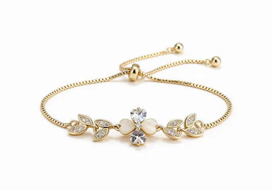 Gold box chain adjustable bracelet featuring a four-petal flower made of mother-of-pearl and clear zircon hearts, surrounded by symmetrical pave zirconia leaves.