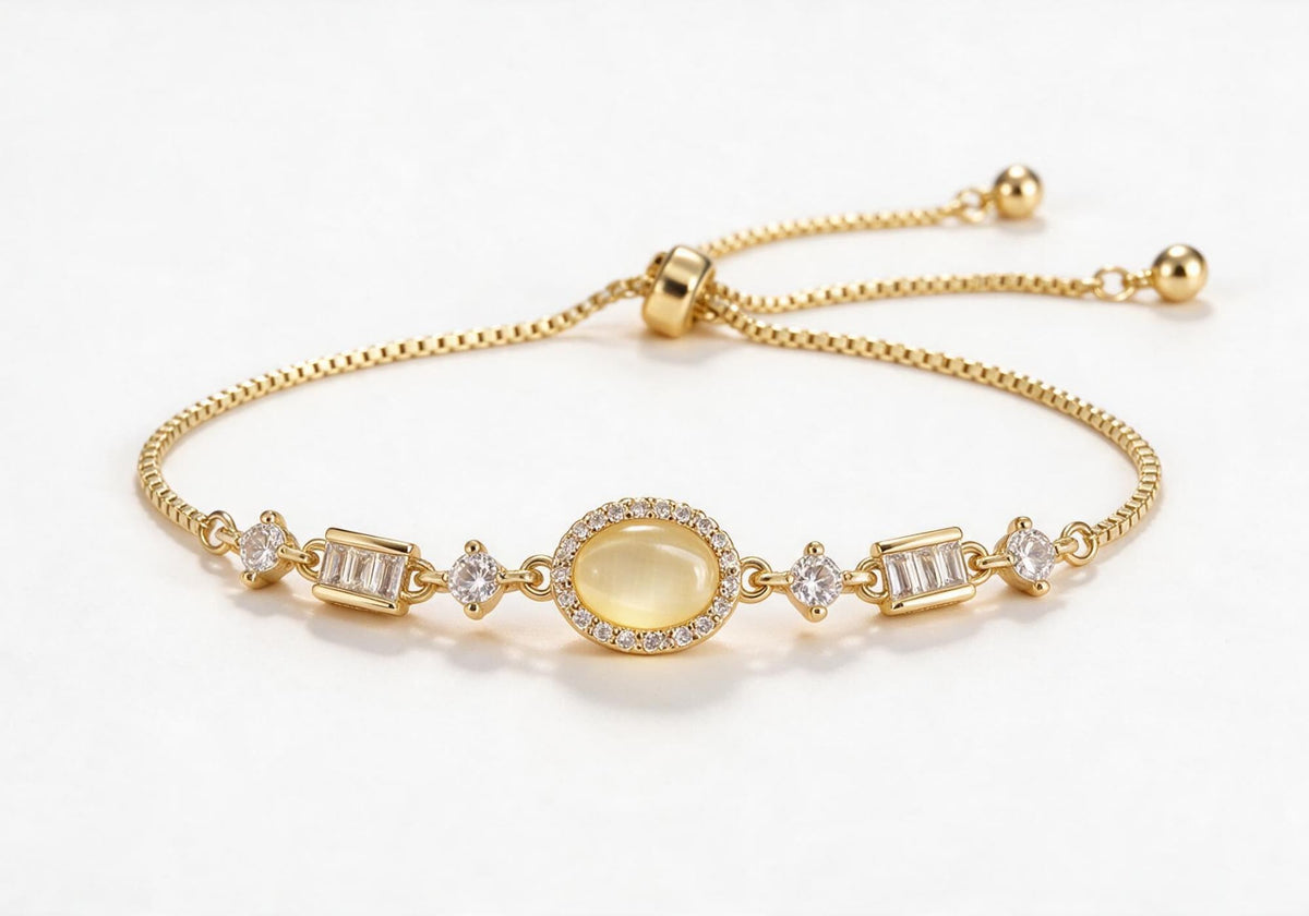 Gold box chain adjustable bracelet featuring an oval warm yellow cat-eye stone with a zircon halo and alternating round and baguette-cut clear zirconia.