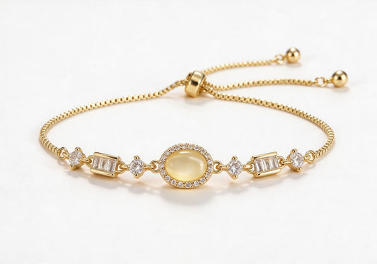 Gold box chain adjustable bracelet featuring an oval warm yellow cat-eye stone with a zircon halo and alternating round and baguette-cut clear zirconia.